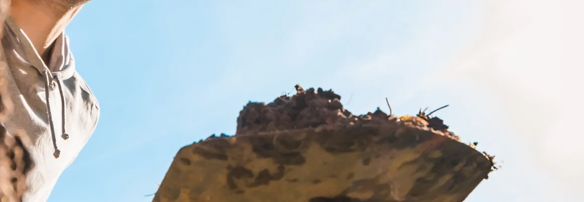 Person hält Spaten mit Erde